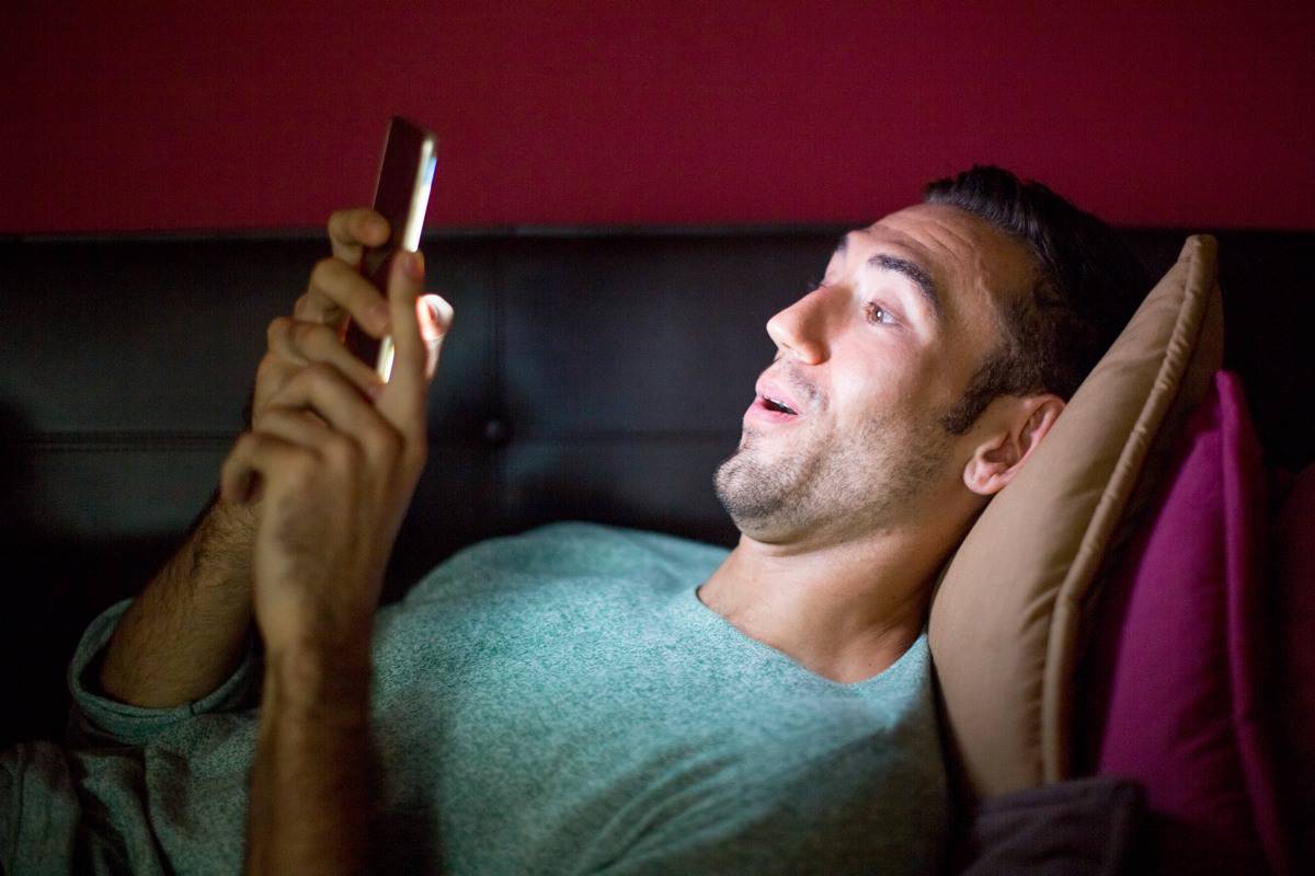 Surprised Man Using Smartphone on Sofa at Night