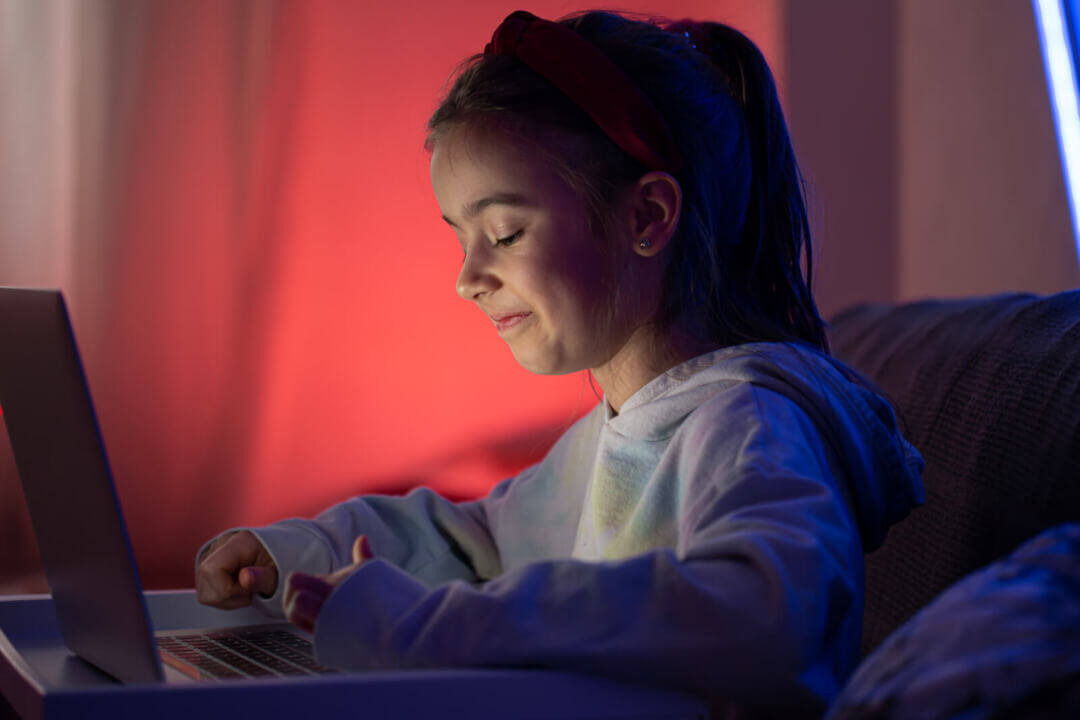 A little girl uses a laptop late at night.