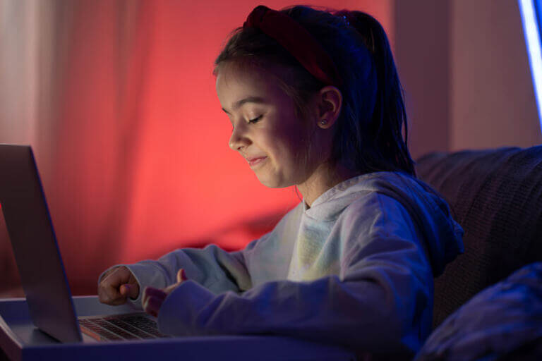 A little girl uses a laptop late at night.